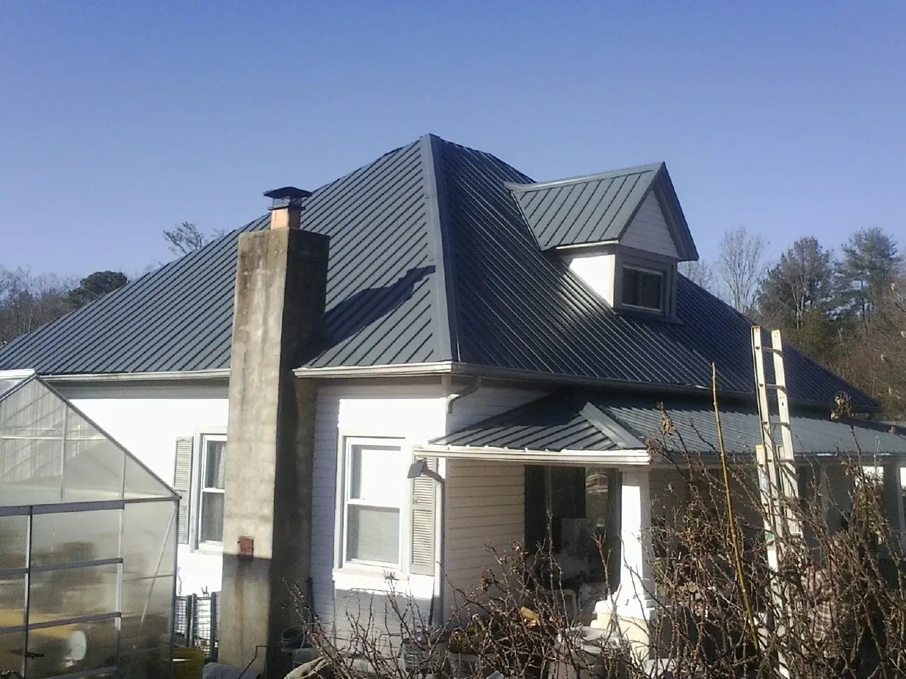 Dark blue standing seam metal roof on a white farmhouse with dormer — Slate & Tile Roof Repair by Roofing Brothers in Owenton