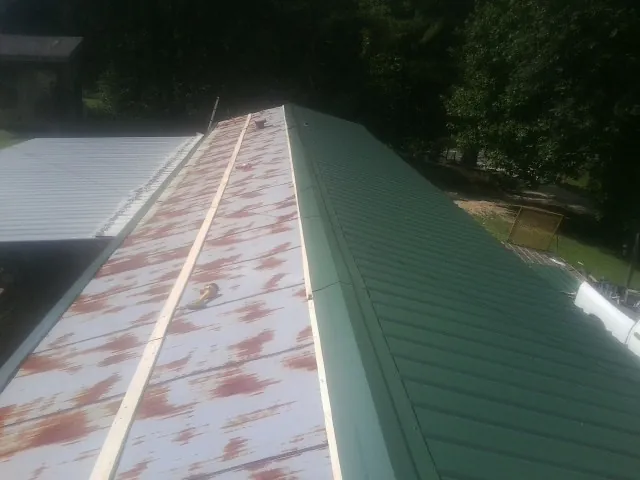 Old rusted panels beside newly installed green metal roofing — Wind Damage Roof Repair by Roofing Brothers in Owenton