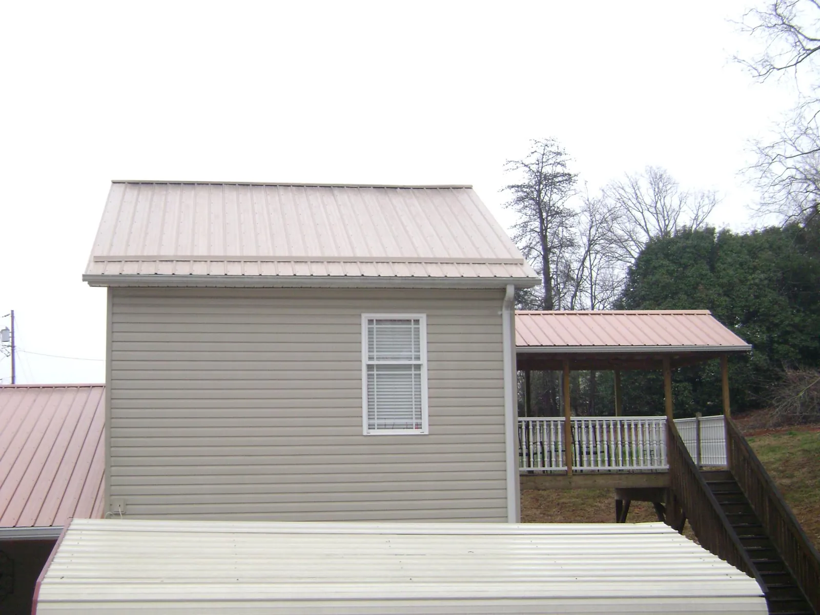 Tan metal roofs on a two story addition and attached porch, from a Roof Replacement job in Owenton