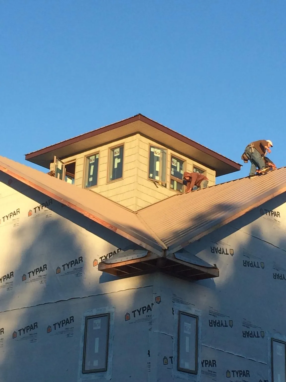Roofers working around a rooftop cupola on a new metal roof at sunset — Roof Waterproofing in Owenton by Roofing Brothers